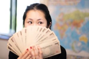 お札を顔の前で広げる女性